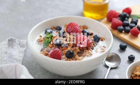 Bol de granola avec myrtilles fraîches, framboises et lait d'amande. Repas santé pour le petit déjeuner ou en-cas Banque D'Images