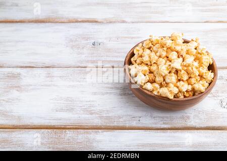 Pop-corn au caramel dans un bol en bois sur fond de bois blanc. Vue latérale, espace de copie. Banque D'Images