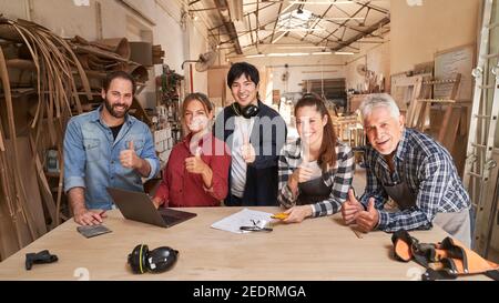 Groupe d'artisans en tant qu'équipe de menuiserie avec les pouces vers le haut dans l'atelier Banque D'Images