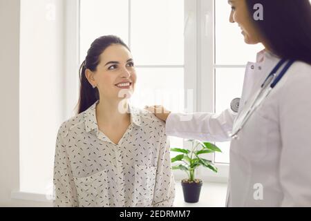Bonne belle jeune femme regardant son médecin amical pendant visite à l'hôpital Banque D'Images
