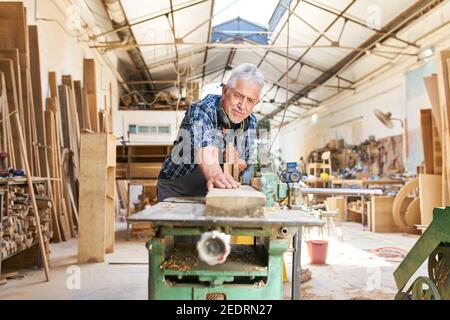 Un artisan senior travaille sur la fraiseuse dans l'atelier de menuiserie Banque D'Images