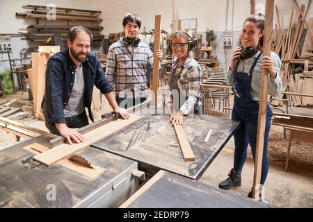 L'équipe d'artisans avec des apprentis et des formateurs dans la menuiserie à la scie circulaire Banque D'Images