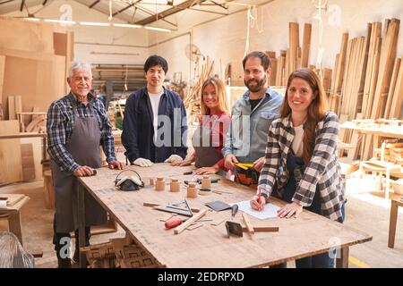 Groupe d'artisans en tant qu'équipe de charpentier dans la menuiserie atelier avec des apprentis Banque D'Images