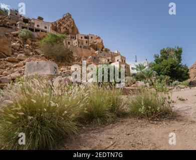 Un vieux village dans la gorge de Wadi Tiwi en Oman par une chaude journée. Les maisons ont collé à la falaise abrupte. Banque D'Images