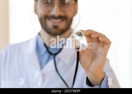 Gros plan souriant jeune homme beau médecin tenant le stéthoscope. Banque D'Images