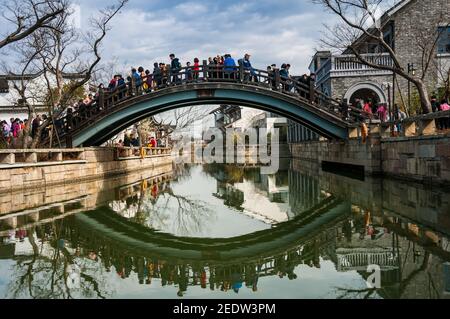 Personnes traversant un pont près de l'entrée principale de Guangfuin dans le quartier de Songjiang à Shanghai. Banque D'Images