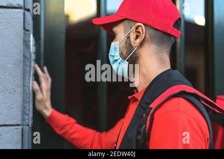 Homme pilote qui fournit des repas à la maison des clients tout en portant le visage Masque pendant l'épidémie de virus corona - concept de la livraison de nourriture Banque D'Images