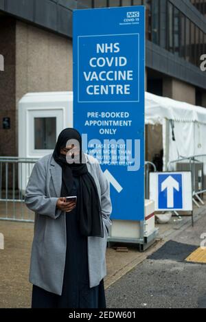 Londres, Royaume-Uni. 15 février 2021. Une femme musulmane quitte le centre de vaccination de masse du Centre du Bureau olympique de Wembley, dans le nord de Londres, après avoir été vaccinée. Les membres des minorités noire, asiatique et ethnique seraient moins susceptibles de demander une vaccination. Au cours du week-end, le gouvernement britannique a atteint son objectif d'administrer 15 millions de premières doses de Covid-19 d'ici le 15 février et l'objectif est maintenant de vacciner tous les plus de 50 ans d'ici la fin avril. Credit: Stephen Chung / Alamy Live News Banque D'Images