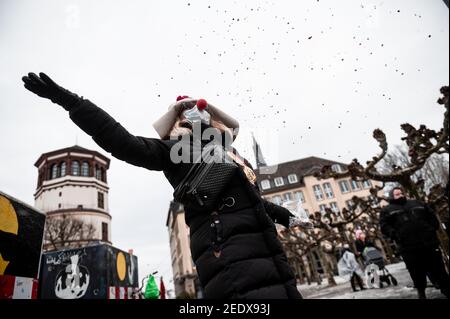 Düsseldorf, Allemagne. 15 février 2021. Une femme déguisée jette des confettis dans l'air. Les Carnivalistes de Düsseldorf ont envoyé huit de leurs célèbres « voitures otto » dans les rues le lundi de la Rose. En raison de la pandémie, les caricatures plus grandes que nature ne voyageront pas dans la ville à titre de procession, mais séparément. Credit: Fabian Strauch/dpa/Alay Live News Banque D'Images