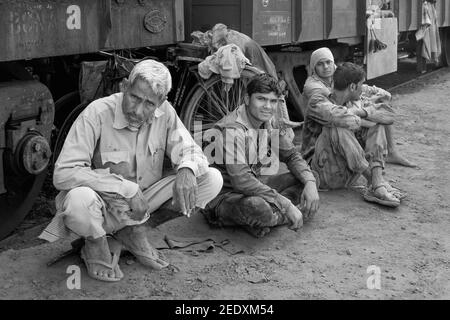 Les travailleurs manuels employés pour déplacer de lourds sacs de ciment profitent d'une pause aux côtés du chemin de fer à Mathura, Uttar Pradesh, Inde. Banque D'Images