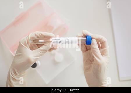 Vue de dessus gros plan de la femme médecin tenant le test d'anticorps covid sur le bureau à la clinique médicale, espace de copie Banque D'Images