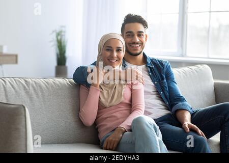 Couple arabe positif posant sur le canapé à la maison Banque D'Images