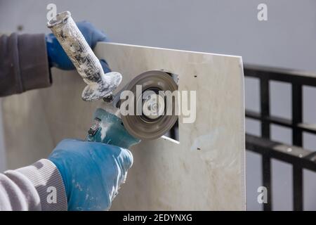 Meuleuse d'angle avec une découpe de carreaux de céramique une ouverture carrée un trou dans la mosaïque Banque D'Images