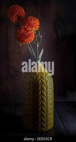 Bouquet de fleurs orange d'automne dans une carafe isolée sur fond d'effet de bois. Banque D'Images