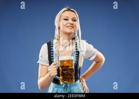 Blonde allemande jeune femme en costume traditionnel avec une pinte de bière Banque D'Images