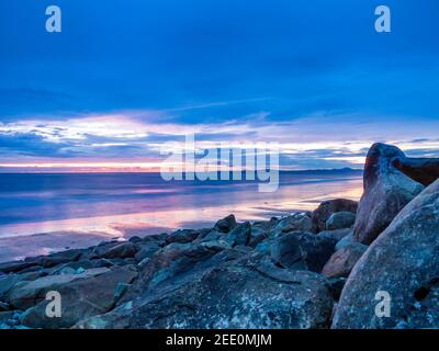 Coucher de soleil sur la plage à Tal y Bont Barmouth Bay ou Abermaw à Gwynedd sur la côte nord-ouest du pays de Galles avec les montagnes de Snowdonia à distance de tne. Banque D'Images