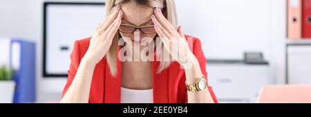 Femme fatiguée en costume d'affaires tenant sa tête à l'ordinateur portable à la table Banque D'Images