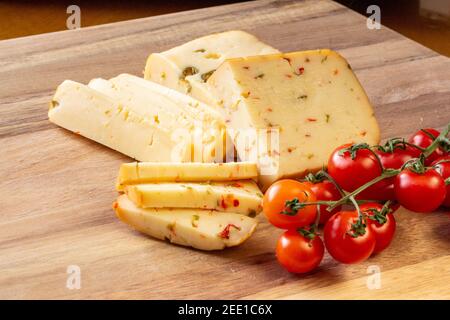 Fromage doux aux olives et fromage aux piments avec tomates et romarin - fond en bois Banque D'Images