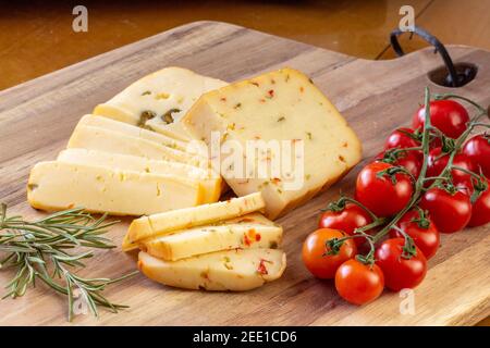 Fromage doux aux olives et fromage aux piments avec tomates et romarin - fond en bois Banque D'Images