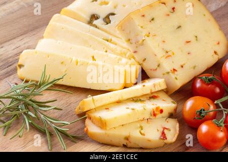 Fromage doux aux olives et fromage aux piments avec tomates et romarin - fond en bois Banque D'Images