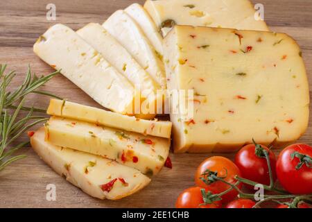 Fromage doux aux olives et fromage aux piments avec tomates et romarin - fond en bois Banque D'Images