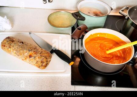 Boulettes entières fraîchement bouillies avec couteau sur le plan de cuisine, sauce tomate bouillonnante chaude avec une cuillère dans la casserole, pots avec du bœuf bouilli sur une table de cuisson en céramique. Prép Banque D'Images