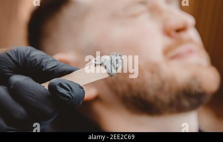 Master barber enlève les cheveux du nez de l'homme avec la cire, épilation procédure de beauté. Banque D'Images