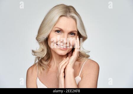 Souriante femme blonde d'âge moyen regardant la caméra annonçant le soin de peau de visage. Banque D'Images