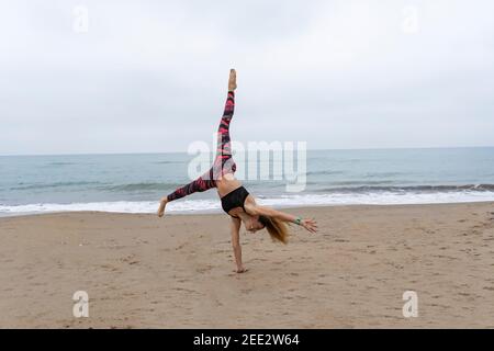 Jeune femme attrayante pratiquant une main debout à la plage.Lifestyle femme sportive entraînement yoga entraînement dehors à la mer Banque D'Images