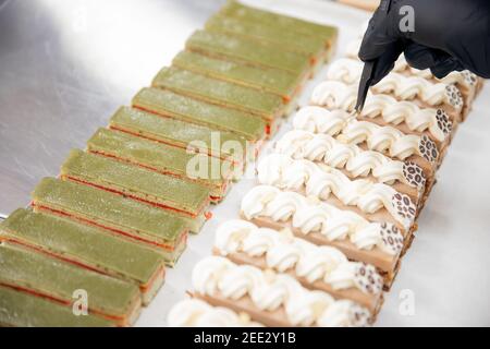 Le chef pâtissier tient des pinces à noix et décorera les gâteaux avant de servir au restaurant. Concept de haute cuisine. Banque D'Images