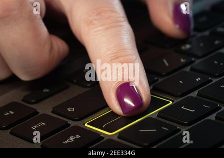 Gros plan du doigt de la femme en appuyant sur la touche entrée du clavier de l'ordinateur portable. Banque D'Images