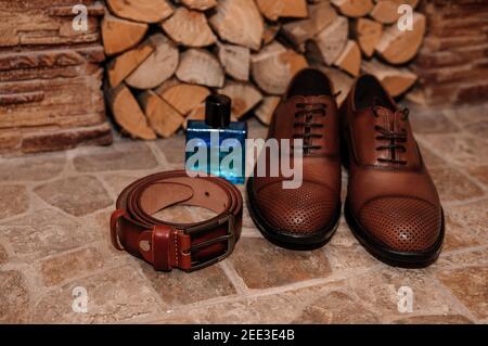 Chaussures brunes pour hommes. Ceinture. Parfum. Anneaux de mariage. Accessoires pour marié Banque D'Images