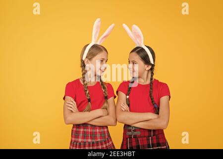 Jeux traditionnels de Pâques. Équipe de Bunny. Concept de divertissement et d'événement. Vacances de printemps. Enfants dans les oreilles de lapin de lapin. Famille et Sisterhood. Uniforme scolaire pour petites écolières avec de longues oreilles de lapin. Banque D'Images