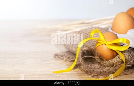 Oeufs de Pâques avec un ruban d'or sur un Burlap sur un fond clair. Bannière concept joyeuses Pâques. Copier l'espace, Flat lay Banque D'Images