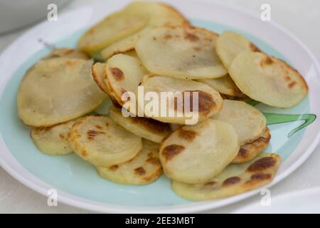 Tranches de pommes de terre cuites au four, servies sur une assiette colorée Banque D'Images