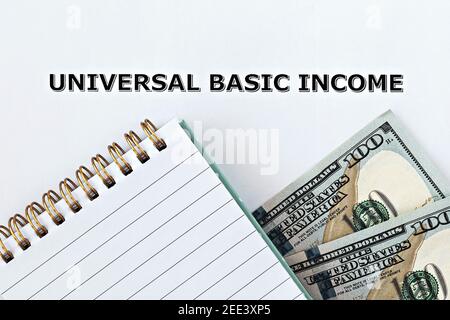Photo TopView sur le thème du revenu de base universel. Les mots revenu de base universel sur papier, entourés de billets en dollars et d'un bloc-notes Banque D'Images