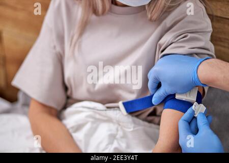 un médecin en milieu de culture en gants médicaux injecte le bras du patient à la maison en quarantaine. un médecin donne une dose de vaccination à une jeune femme patient a. Banque D'Images