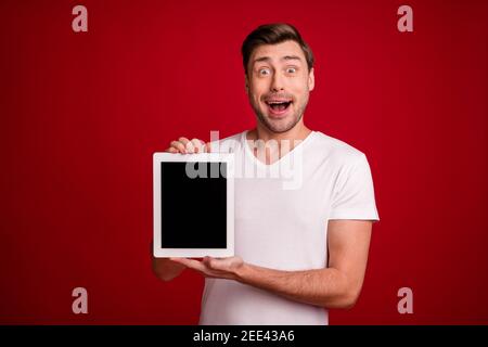 Photo portrait d'un entrepreneur surpris montrant l'écran tactile vide de la tablette espace ouvert bouche isolé couleur rouge vif arrière-plan Banque D'Images