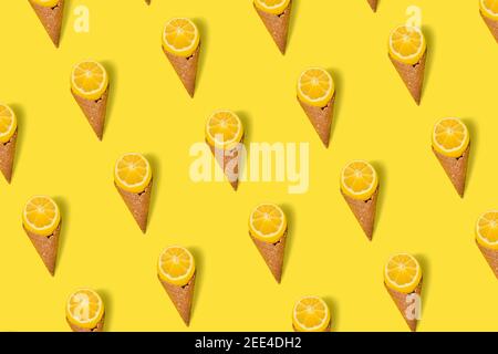 Motif Couper le citron avec le cône de glace sur fond jaune lumineux. Pose à plat. Concept de crème glacée aux fruits Banque D'Images