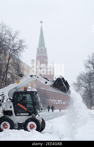 Moscou. Russie. 12 février 2021. Un petit bobcat de pelle-chargeuse enlève la neige du trottoir près des murs du Kremlin lors d'une forte chute de neige Banque D'Images