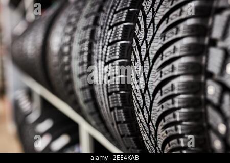 gros plan sur les nouveaux pneus dans le centre de service de réparation automatique, les nouveaux pneus d'hiver avec une bande de roulement moderne isolée. attention sélective. arrière-plan de la pile de pneus Banque D'Images