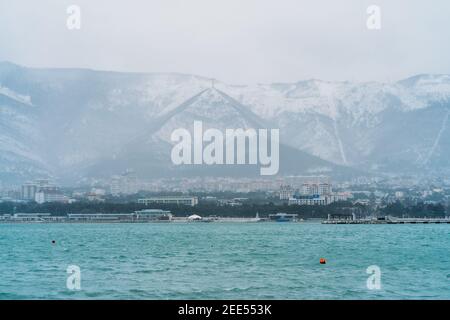 La ville de Gelendzhik en hiver par temps enneigé, les montagnes couvertes de neige, de vagues et de vent sur la surface de la baie de mer, pas de personnes marchant dans la ville. Banque D'Images