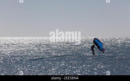 Homme pratiquant avec de l'hydroptère au coucher du soleil dans la mer Banque D'Images