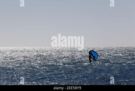 Homme pratiquant avec de l'hydroptère au coucher du soleil dans la mer Banque D'Images