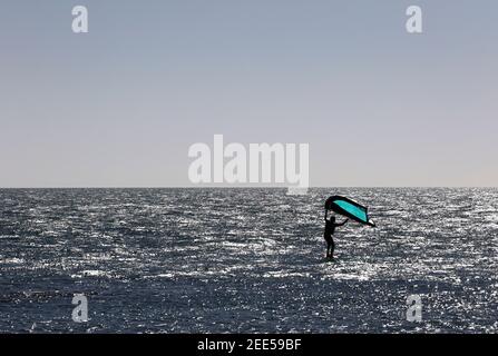 Homme pratiquant avec de l'hydroptère au coucher du soleil dans la mer Banque D'Images