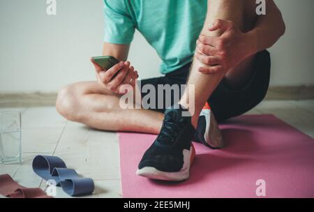 Photo rapprochée d'un homme caucasien allongé sur le portez des vêtements de sport et discutez sur votre téléphone mobile tout en ayant un cours de fitness Banque D'Images