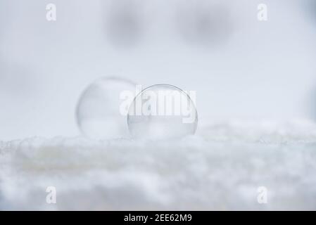 Deux bulles de savon congelées gèlent à basse température sous zéro sur la neige Banque D'Images