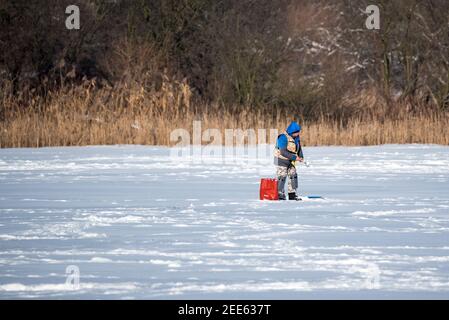 Zegrze, Pologne - 13 février 2021 : pêche sous la glace. Pêcheur à la ligne sur un lac gelé. Sports d'hiver. Les gens sur la glace. Banque D'Images