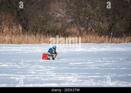 Zegrze, Pologne - 13 février 2021 : pêche sous la glace. Pêcheur à la ligne sur un lac gelé. Sports d'hiver. Les gens sur la glace. Banque D'Images