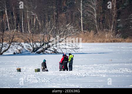 Zegrze, Pologne - 13 février 2021 : pêche sous la glace. Pêcheur à la ligne sur un lac gelé. Sports d'hiver. Les gens sur la glace. Banque D'Images